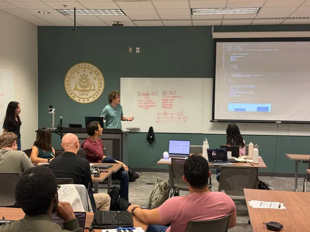 A presenter beside whiteboard notes on the Hadamard gate and Bell states, with Qiskit code and a results histogram on the projector.